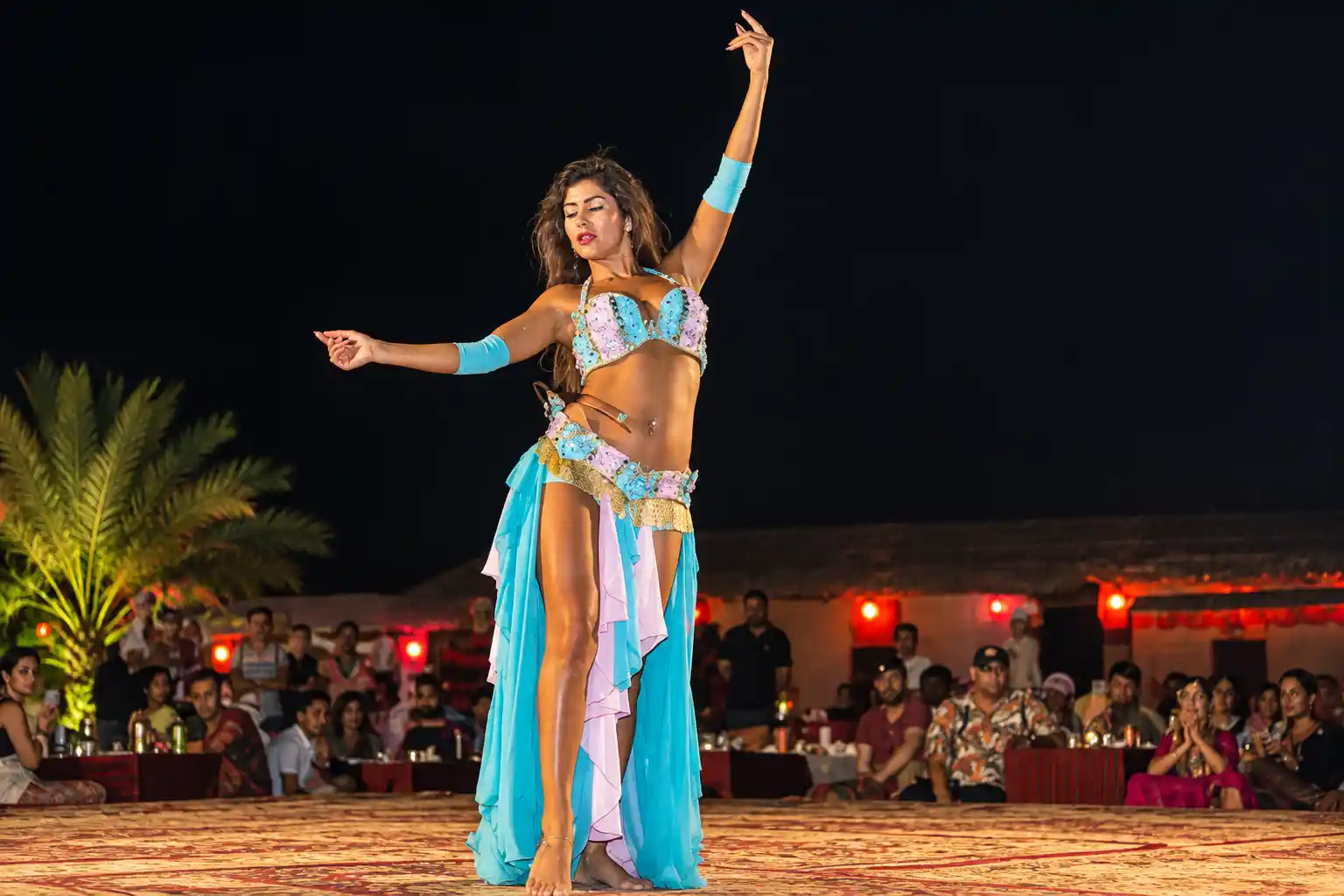 Professional belly dancer performing live onstage during an evening desert safari show in Dubai.