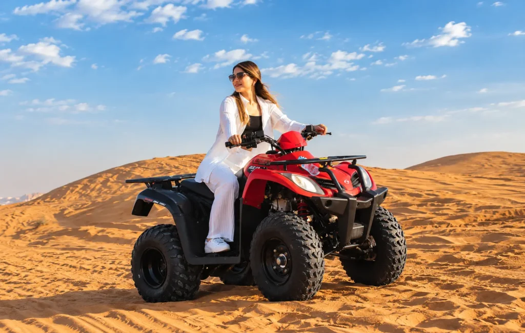 Woman riding a red ATV during a quad biking Dubai adventure across desert dunes.