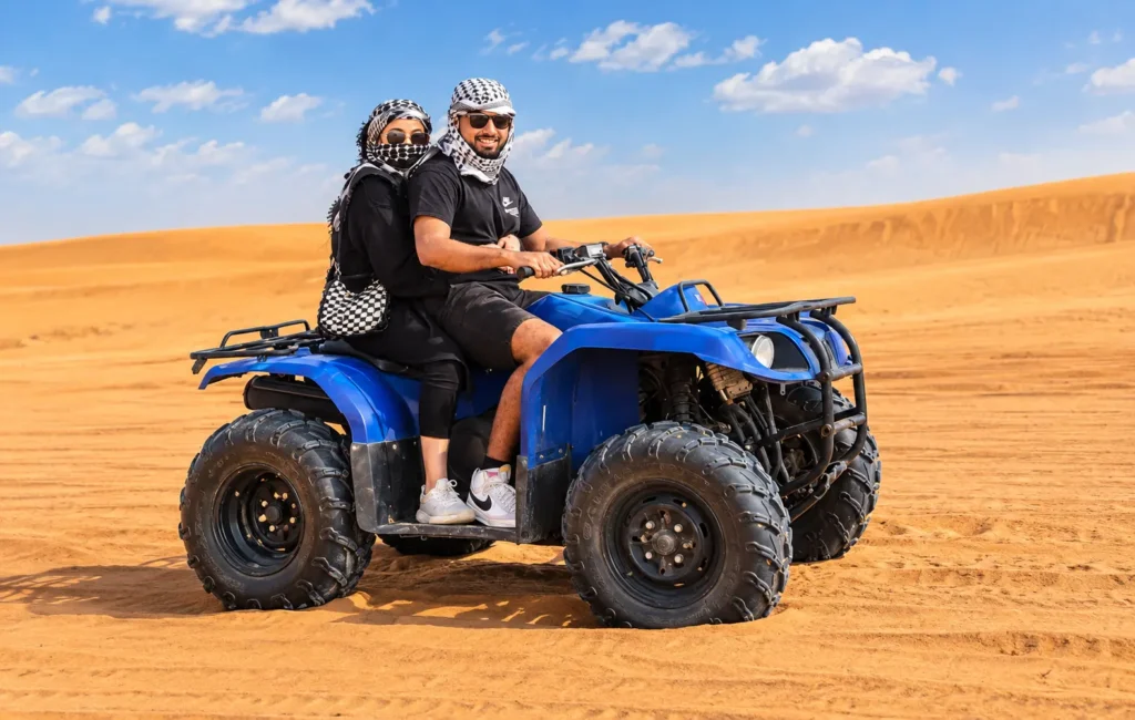 Two riders on a double-seater quad bike exploring open desert dunes during quad biking Dubai.