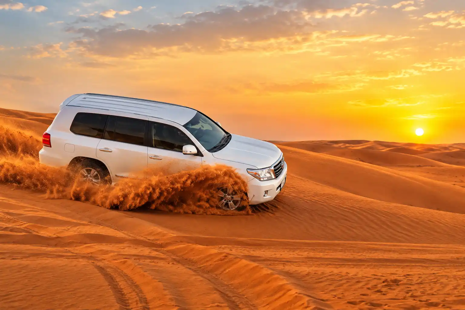 A white 4x4 vehicle dune bashing across golden sand dunes during an evening desert safari in Dubai.