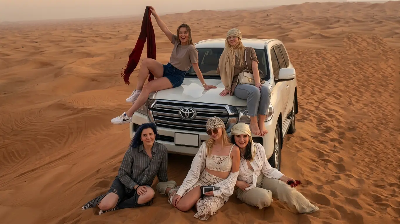 Group of friends posing on and around a 4x4 Land Cruiser during a private desert safari in Dubai