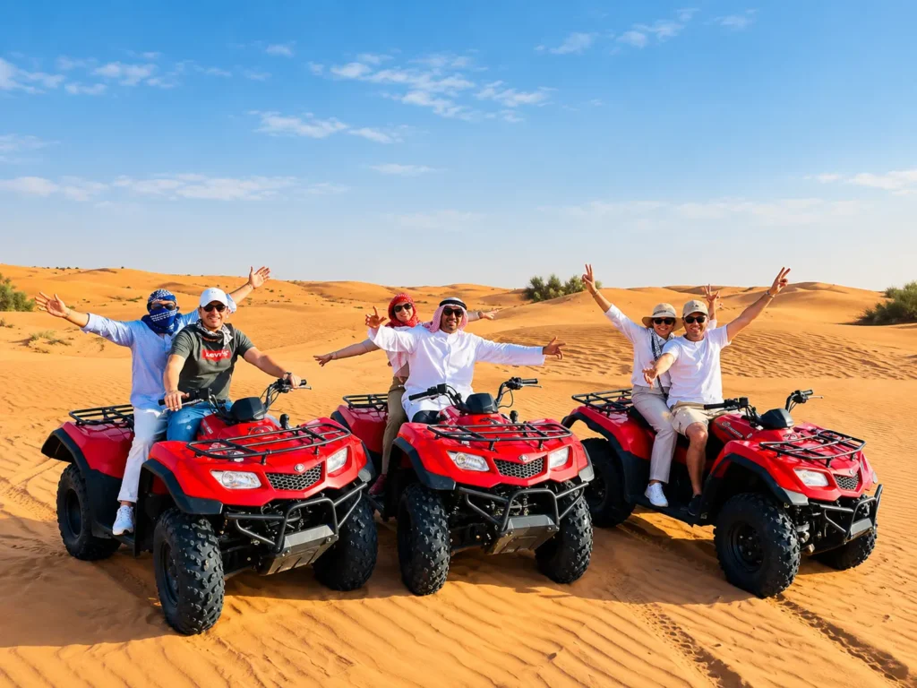 Group of tourists posing on red quad bikes across golden sand dunes in the desert.