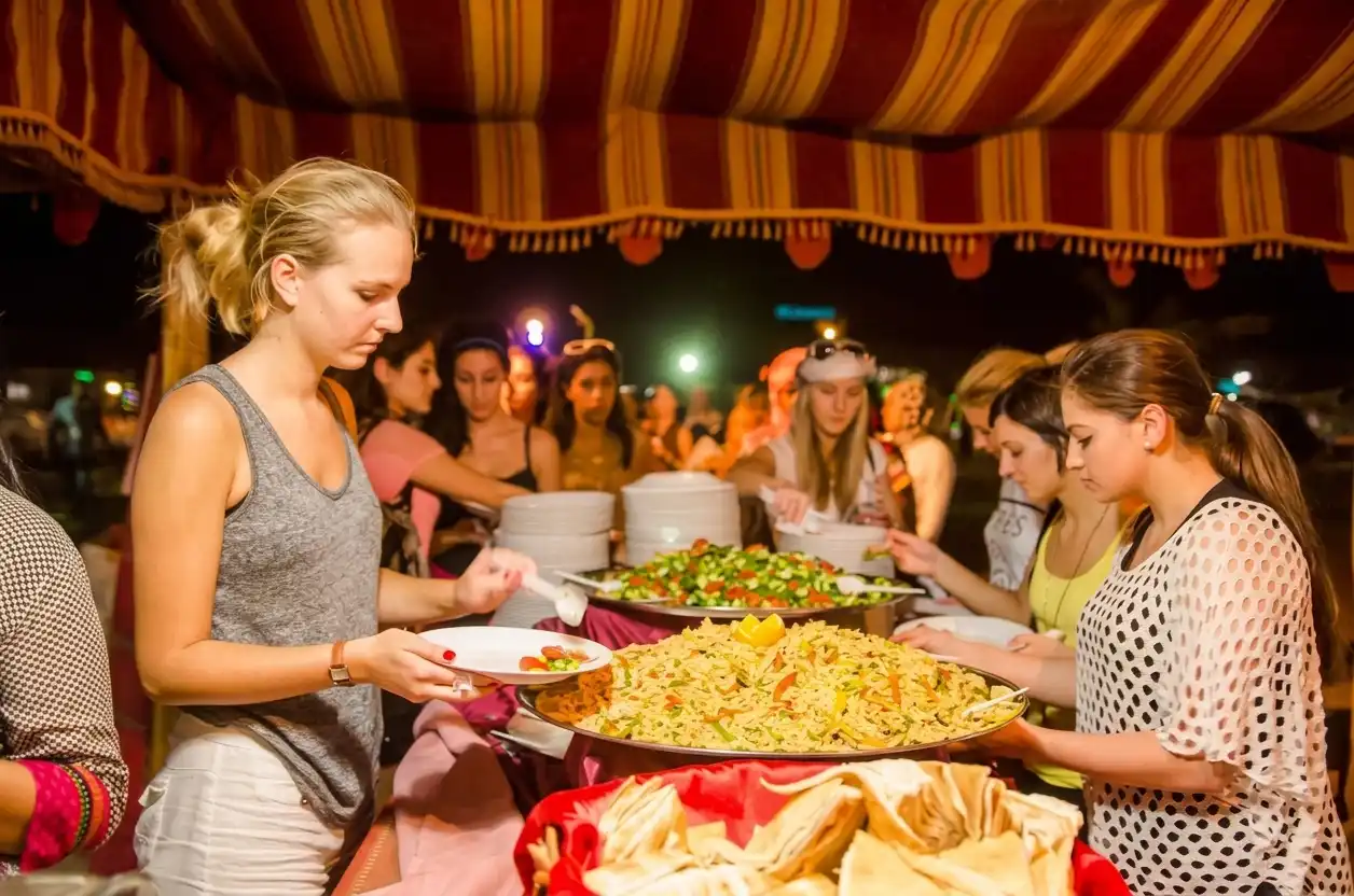 Guests serving food from an international BBQ buffet spread at the desert camp in Dubai