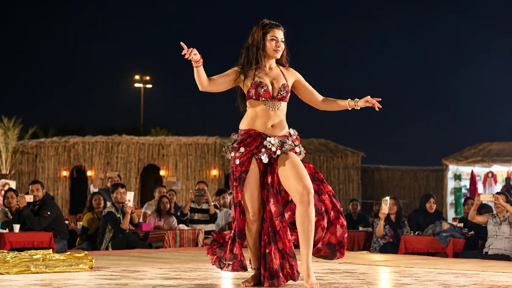 Female belly dancer performing live entertainment in traditional costume at a Dubai desert camp.