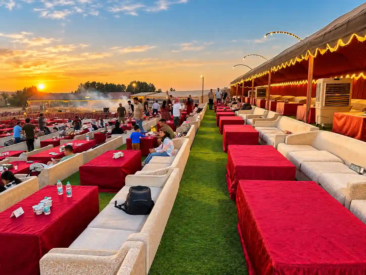 Guests relaxing at a desert camp with low seating tables during a sunset safari in Dubai